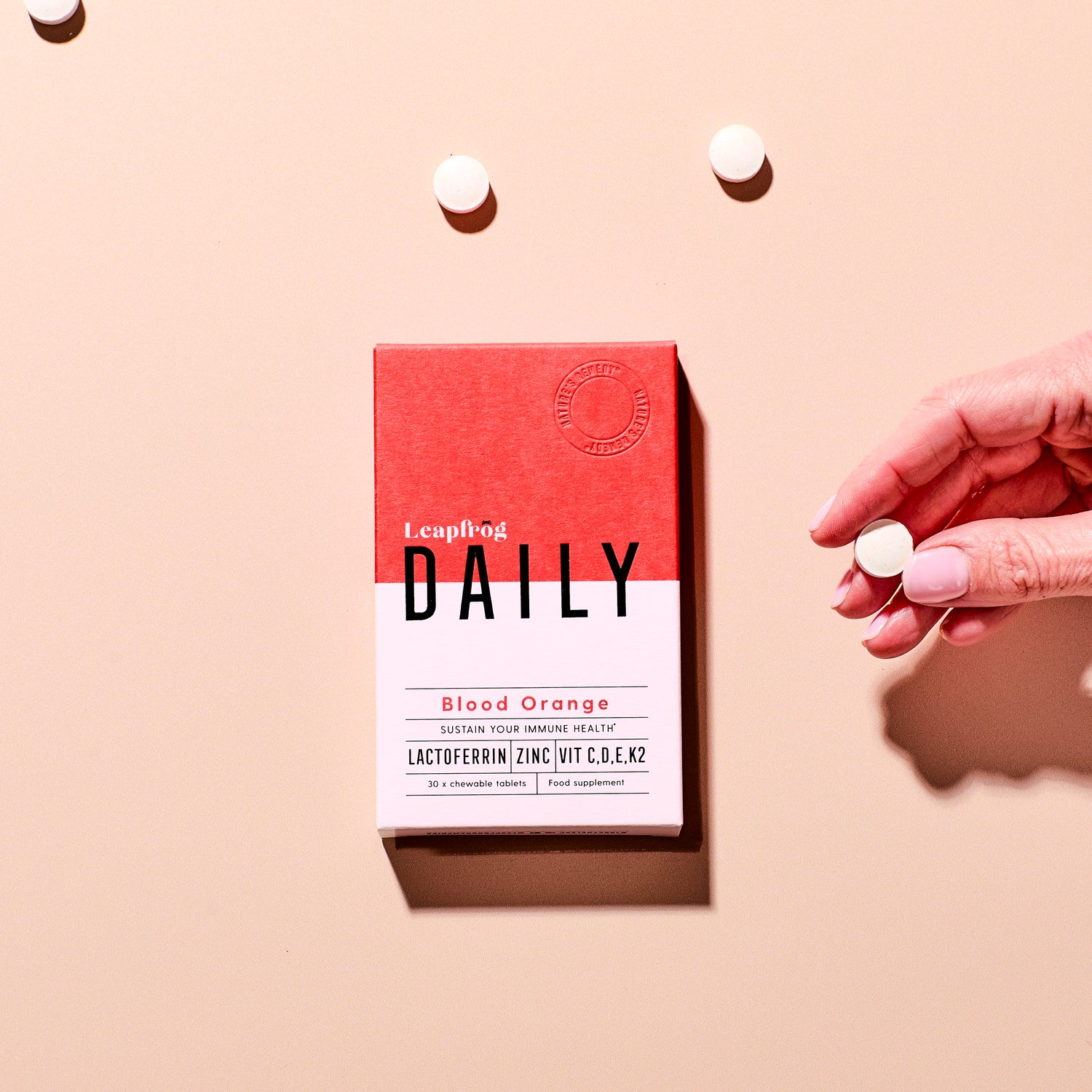Box of Leapfrog Daily immune supplement with a hand holding a chewable tablet 