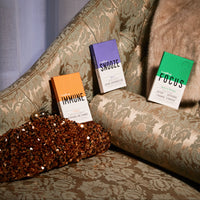 Three supplements labelled 'Immune', 'Snooze', 'Focus' on a patterned sofa - natural supplements for immunity, sleep and stress